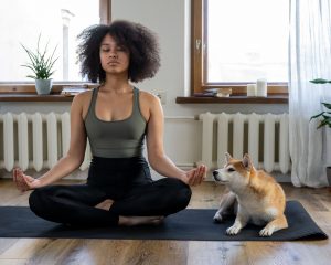 Woman doing yoga next to her dog.